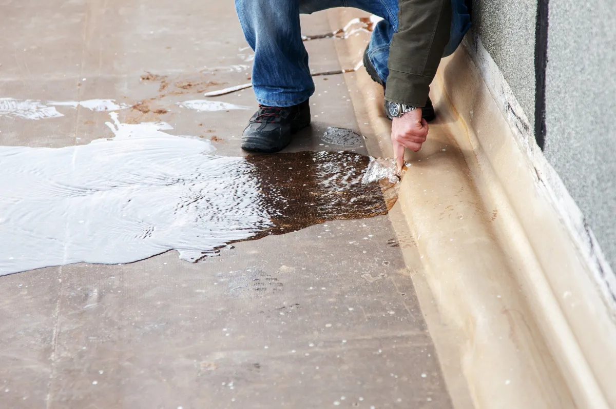 Water spreading across a floor from a leak at the base of a wall